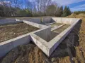 Solidna papa fundamentowa tworzy podstawę dla przyszłego domu. Betonowe ściany fundamentowe otaczają wykop.