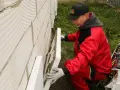 Budowlaniec w czerwonym stroju montuje płyty styropianowe o odpowiedniej grubości na ścianie z bloczków.