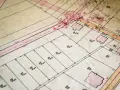 Stara mapa ewidencyjna z zaznaczonymi działkami, budynkami i liniami granicznymi.