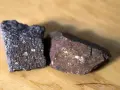 Dwa fragmenty skał, jeden ciemny, drugi czerwonawy, przypominają porfir.