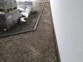 Stos **wapien** w budowie ścieżki wokół domu. Materiały budowlane leżą na ziemi, częściowo przykryte śniegiem.