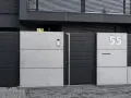 Nowoczesne ogrodzenie domu z betonowych płyt i ciemnoszarych paneli. Elegancki pomysł na ogrodzenie domu z numerem 55.