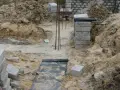 Budowa domu w toku. Widoczne wykopy, zbrojenie i materiały budowlane, tworzące fundamenty domu.