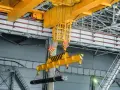 Udt suwnice pytania i odpowiedzi: żółta suwnica podnosi wiązkę prętów w hali produkcyjnej.