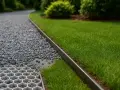 Obrzeże rabaty z trawą i żwirem, przypominającym drobny bazalt.