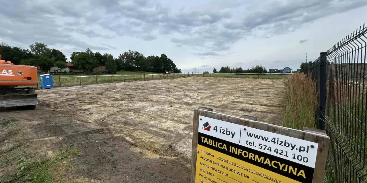 Tablica informacyjna budowy z danymi wykonawcy i adresem inwestycji na placu budowy.