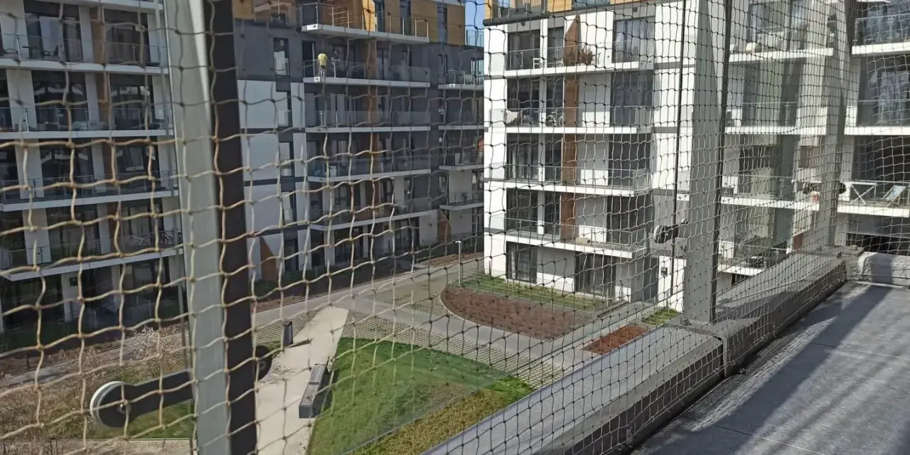 Nowoczesne bloki mieszkalne z balkonami, zabezpieczone siatką. Zastanawiasz się, ile kosztuje montaż siatki na balkonie?