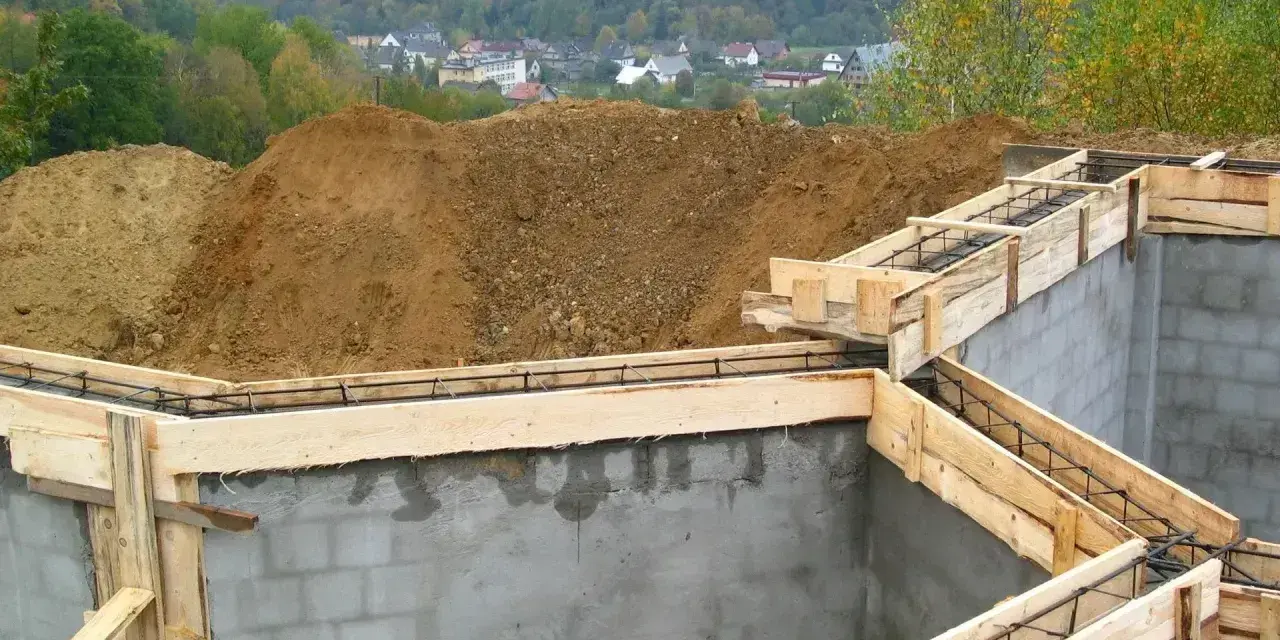 Fundamenty domu w budowie, zbrojenie i szalunki czekają na beton. Widać, ile jest ważne pozwolenie na budowę, by móc rozpocząć taką inwestycję.