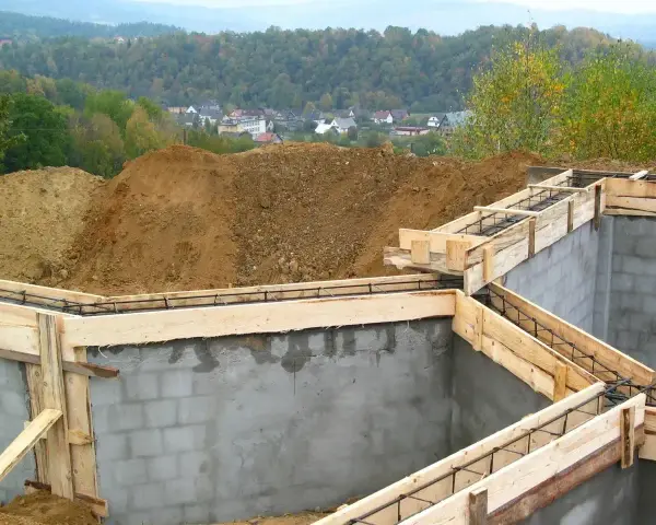 Fundamenty domu w budowie, zbrojenie i szalunki czekają na beton. Widać, ile jest ważne pozwolenie na budowę, by móc rozpocząć taką inwestycję.