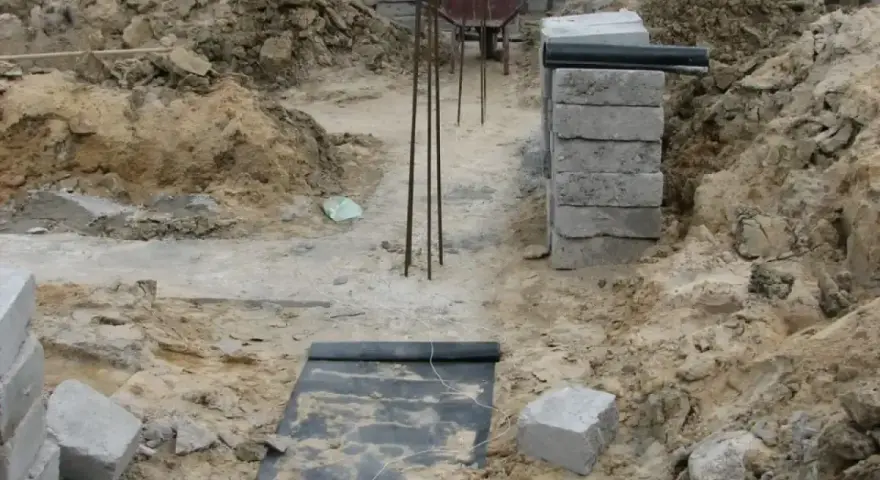 Wykonano wykopy pod fundamenty. Widać zbrojenie, betonowe bloczki i ziemię.