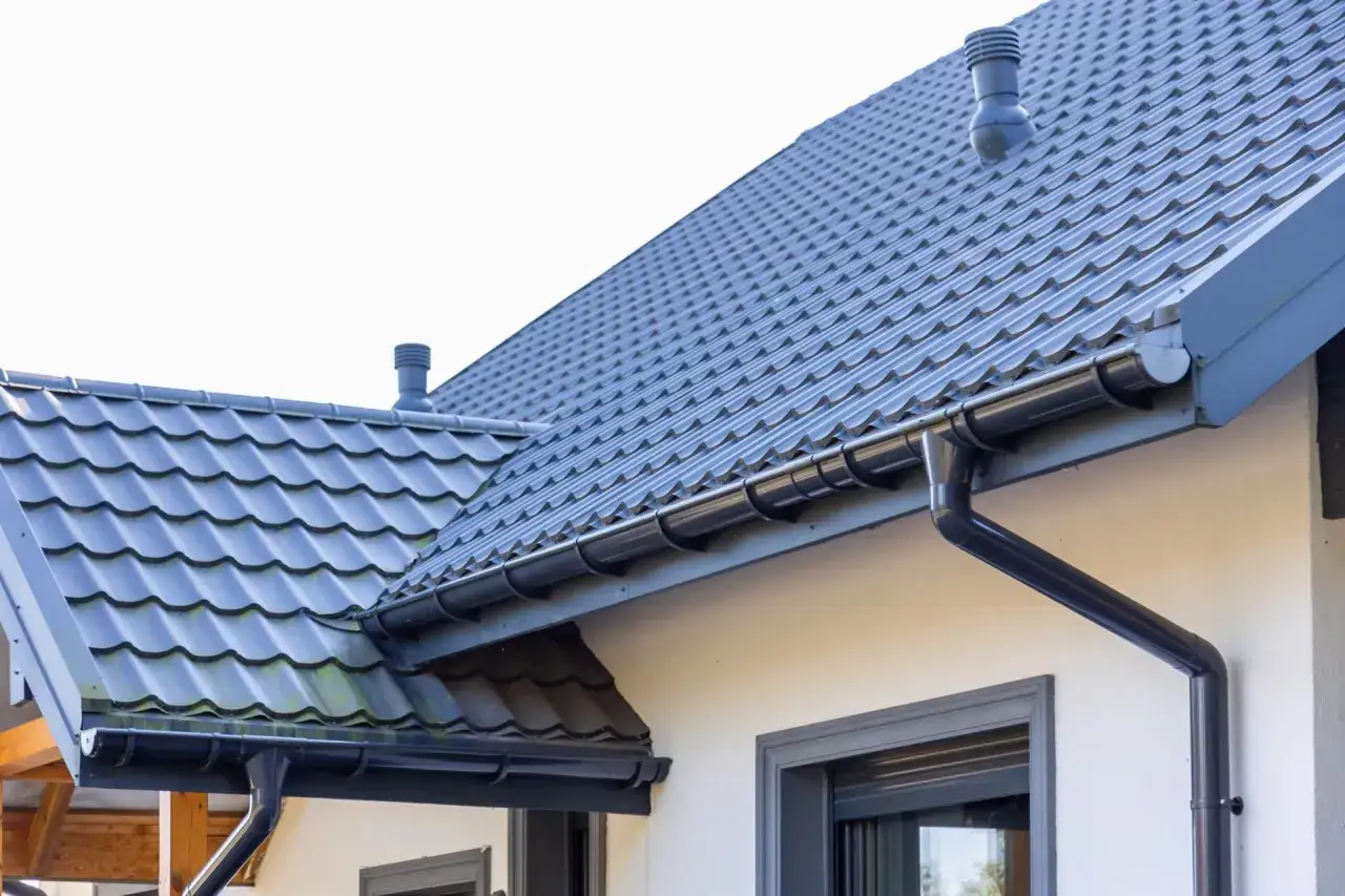 Szary dach z dachówki ceramicznej, rynny i komin. Sprawdź aktualną dachówka ceramiczna cena za m2.